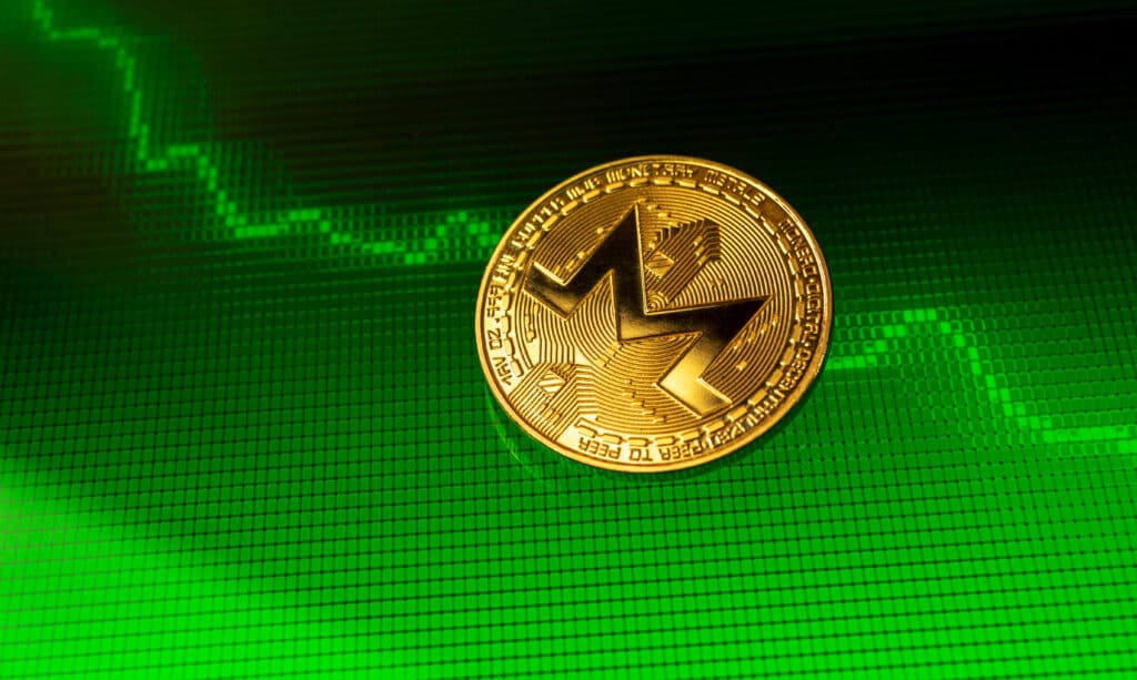 A Monero coin on a digital screen with a cryptocurrency chart in the background
