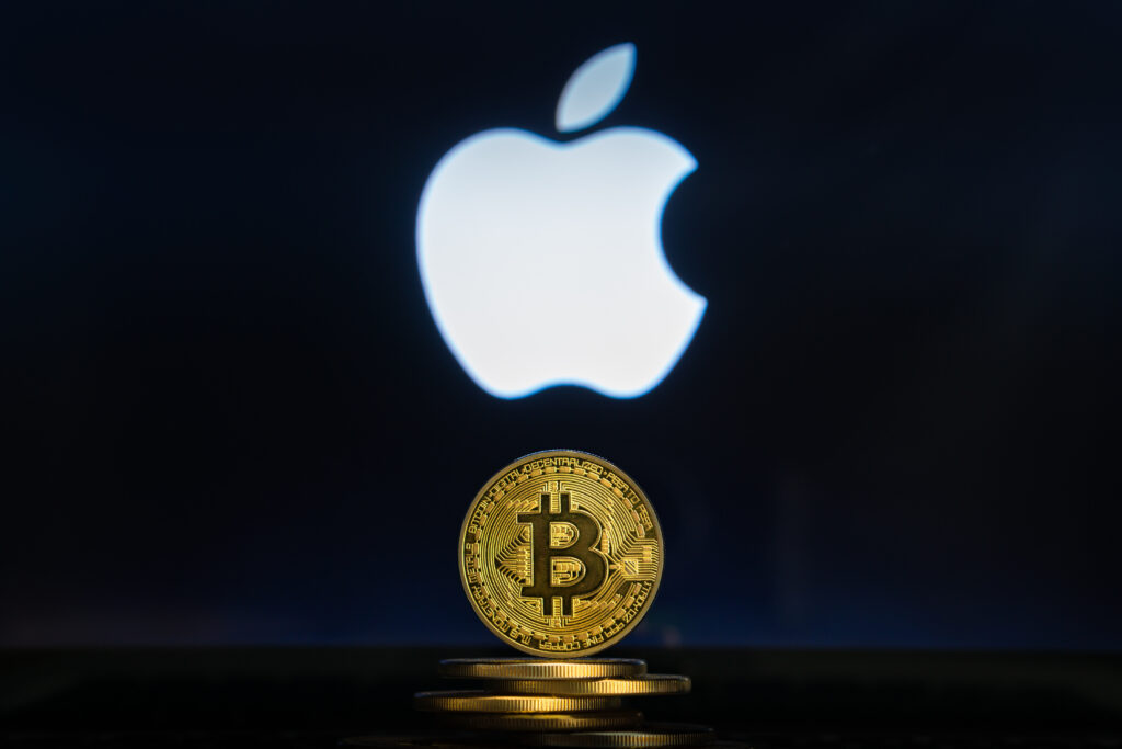 Bitcoin on a stack of coins with Apple logo on a laptop screen.