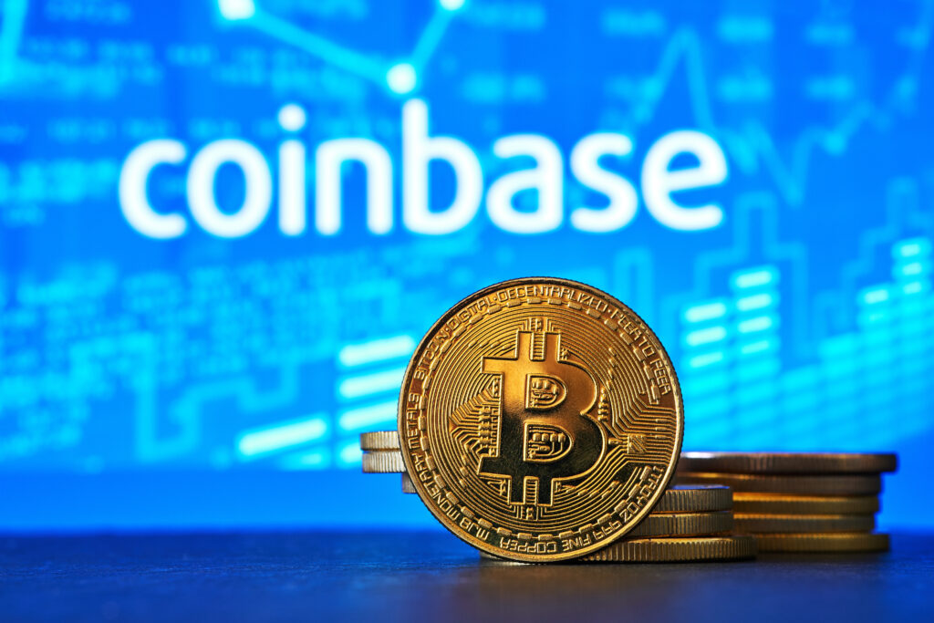 Coinbase logo on a computer screen with a stack of crypto coins