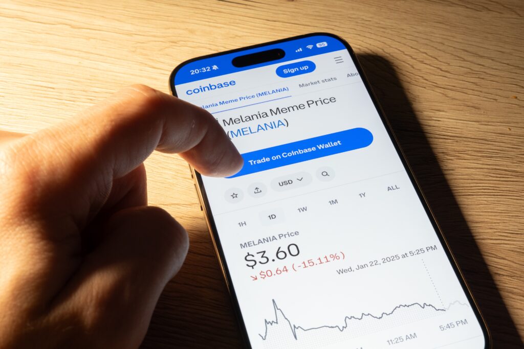 Hand clicking on Coinbase website to buy official Melania meme coin cryptocurrency