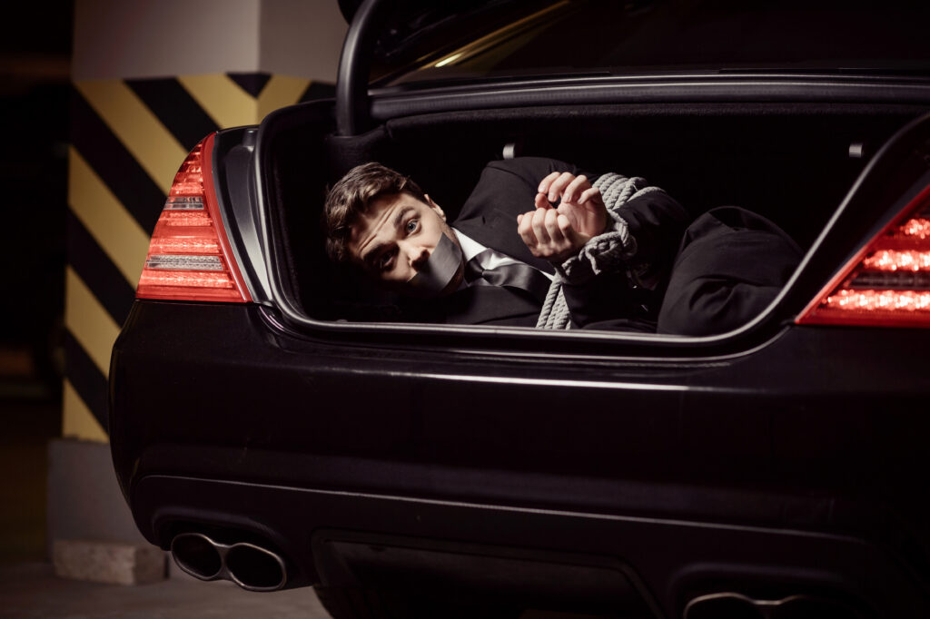 Kidnapped businessman. Tied up businessman lying in the car trun
