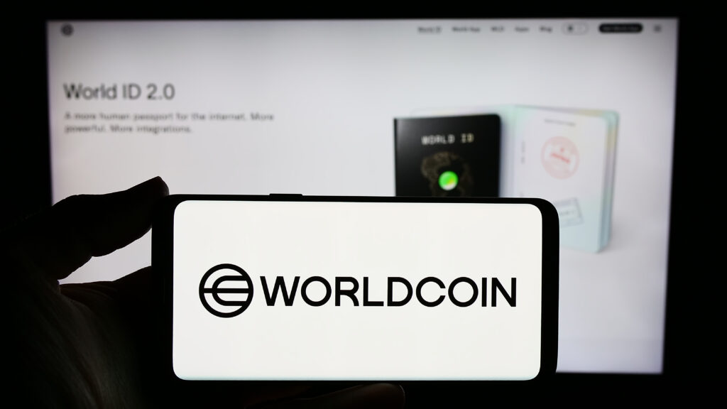 Person holding smartphone with logo of cryptocurrency project Worldcoin (Tools for Humanity) in front of website.