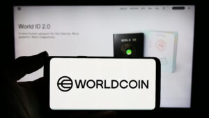 Person holding smartphone with logo of cryptocurrency project Worldcoin (Tools for Humanity) in front of website.