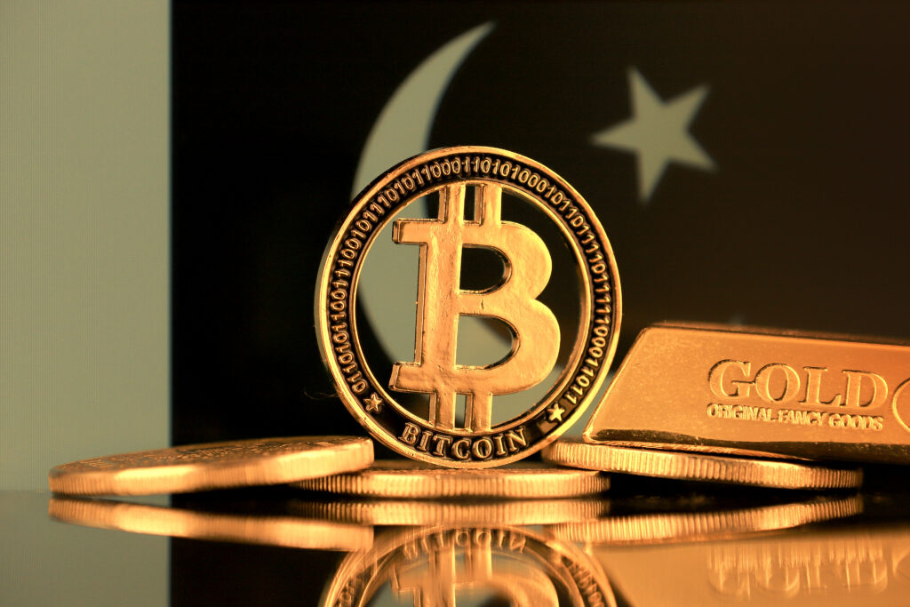 Physical version of Bitcoin, gold bar and Pakistan Flag.