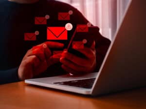 SMS or email spam, fake text message phishing from scammer concept. Many red envelope with system hacked warning alert icon, scam malware spreading virus on message showing on mobile phone in hand.