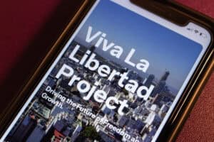The smartphone displays Viva La Libertad Project website.