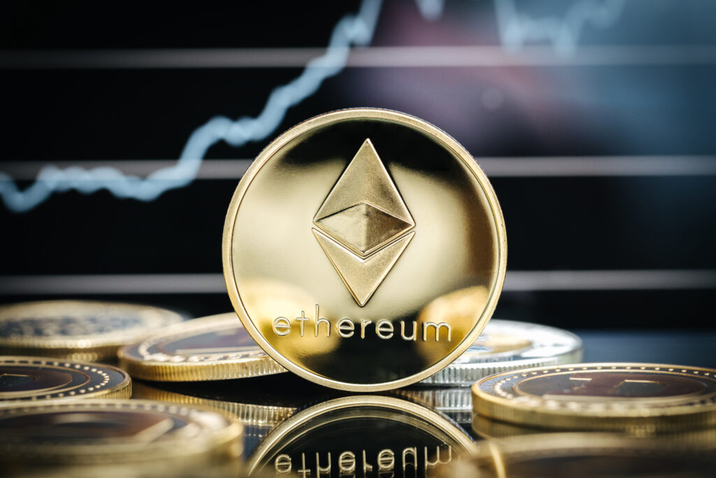 Ethereum cryptocurrency, physical coin close-up in front of a price chart