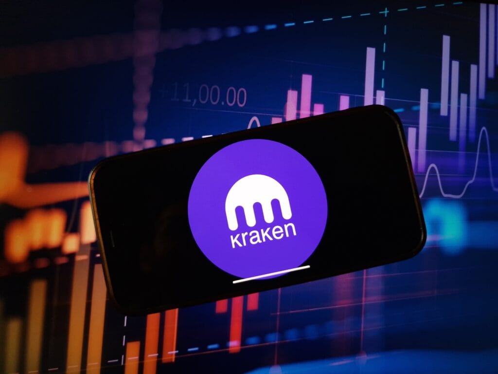 Kraken cryptocurrency exchange logo displayed on smartphone on crypto market data background