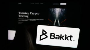 Person holding cellphone with logo of US crypto trading company Bakkt Holdings Inc. in front of business webpage. Focus on phone display.