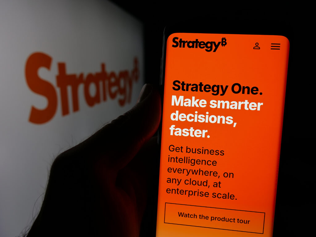 Person holding smartphone with web page of US company MicroStrategy Inc. on screen in front of logo.