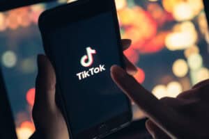 Tik Tok application icon on iPhone 11 pro max screen in hand and have a bokeh for background.