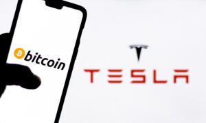 Bitcoin logo on a smartphone against Tesla logo in the background. Elon Musk recently invested $1.5 billion in Bitcoin, opening possibility of Bitcoin transactions to purchase Tesla automobiles.
