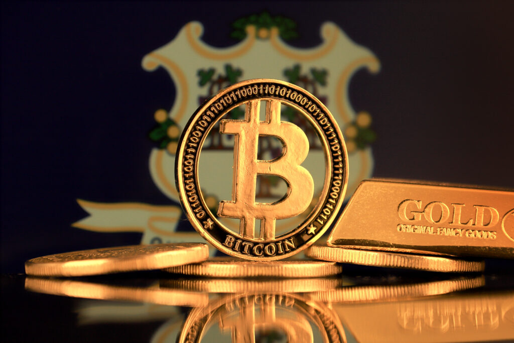 Physical version of Bitcoin, gold bar and Connecticut State Flag.