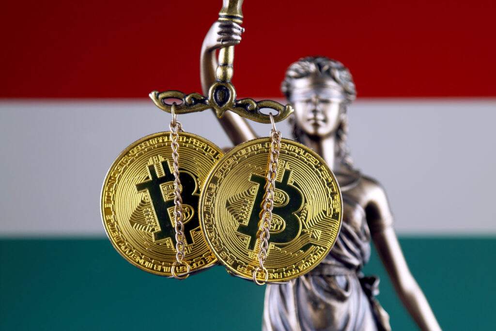 Symbol of law and justice, physical version of Bitcoin and Hungary Flag. Prohibition of cryptocurrencies, regulations, restrictions or security, protection, privacy.