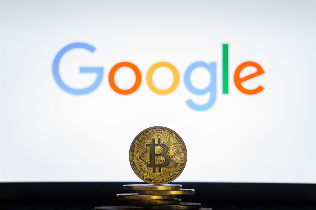 Bitcoin on a stack of coins with Google logo on a laptop screen.