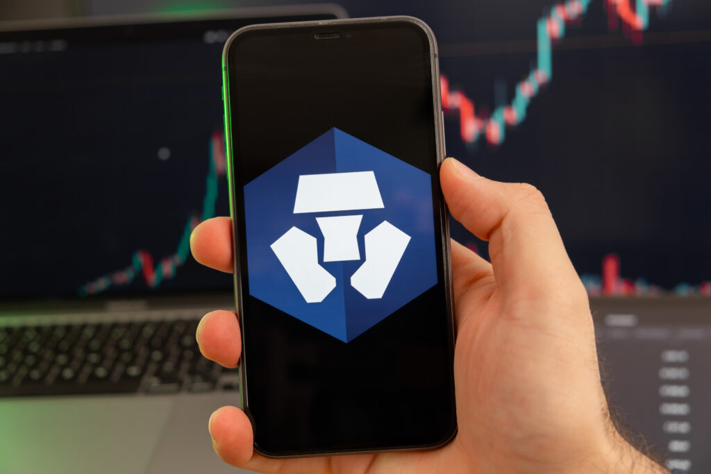 Crypto.com Coin CRO app of cryptocurrency stock market analysis on the screen of mobile phone in man hands and growing charts trading data on the background