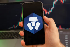 Crypto.com Coin CRO app of cryptocurrency stock market analysis on the screen of mobile phone in man hands and growing charts trading data on the background