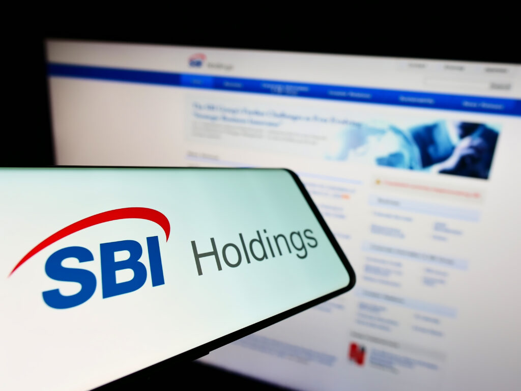 Smartphone with logo of Japanese financial company SBI Holdings on screen in front of business website.