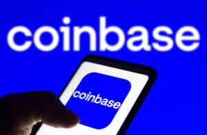 Coinbase logo seen displayed on a smartphone and on the background.