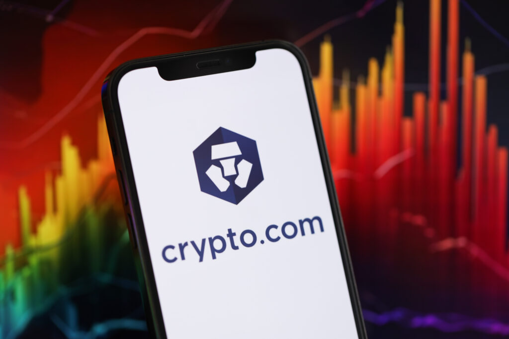 Crypto com logo on iPhone display screen and crypto currency value charts.