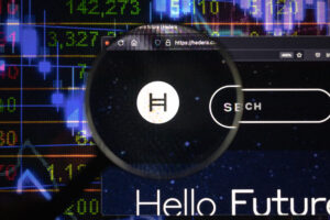 Hedera crypto company logo on a website, seen on a computer screen through a magnifying glass.