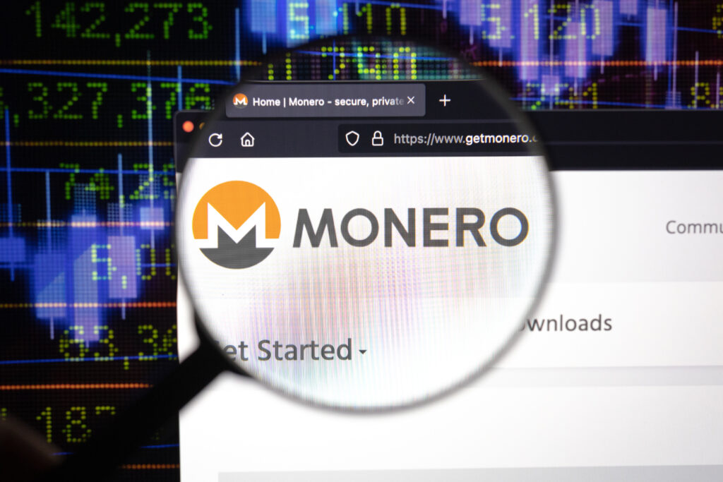 Monero logo on a website, seen on a computer screen through a magnifying glass. Source: Dennis - stock.adobe.com